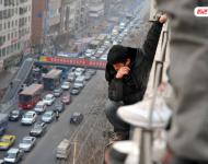 圖為2014年1月3日，蘭州，6名農(nóng)民工為了討薪爬上白銀路一居民樓9樓平臺要“跳樓”。原來，該樓4層的甘肅天安建筑機械工程公司拖欠24名工人的24萬元工錢，他們討要5個月毫無結(jié)果，便做出危險之舉。后經(jīng)有關(guān)部門多方協(xié)調(diào)，工人們當場拿到了18萬元。于永昭/視覺中國
