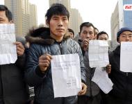 承建商已將工程款給付90%，但包工頭宋林卻把錢拿走不給工人結(jié)工資。一氣之下，十多名工人將包工頭車和人扣下，一不留神卻讓包工頭翻墻跑了。2015年12月31日，在勞動監(jiān)察部門協(xié)調(diào)下達成初步協(xié)議，包工頭將工人手續(xù)移交到成泰公司，由成泰公司替宋林代付一半工資，但在移交工人手續(xù)的時候包工頭害怕再次被扣卻一直不敢露面。1月3日，包工頭給農(nóng)民工發(fā)來短信，并要求寫下承諾書，保證不扣他本人。圖為1月5日，陜西商洛，討薪農(nóng)民工在工地上出示欠條和他們寫給包工頭的承諾書。華商報記者 閆文青/視覺中國