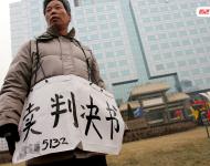 2006年1月24日，在京從事降水井工程的老陳掛著寫有“賣判決書”的紙口袋在北京站口附近來回走著。曾是名小工頭的老陳被欠工程款4萬元，為了給工人們開資不得已賣掉了打井機器。2002年法院宣判老陳勝訴，可四年后該判決仍得不到執(zhí)行，無奈之中老陳只好上演此幕。程寧/視覺中國