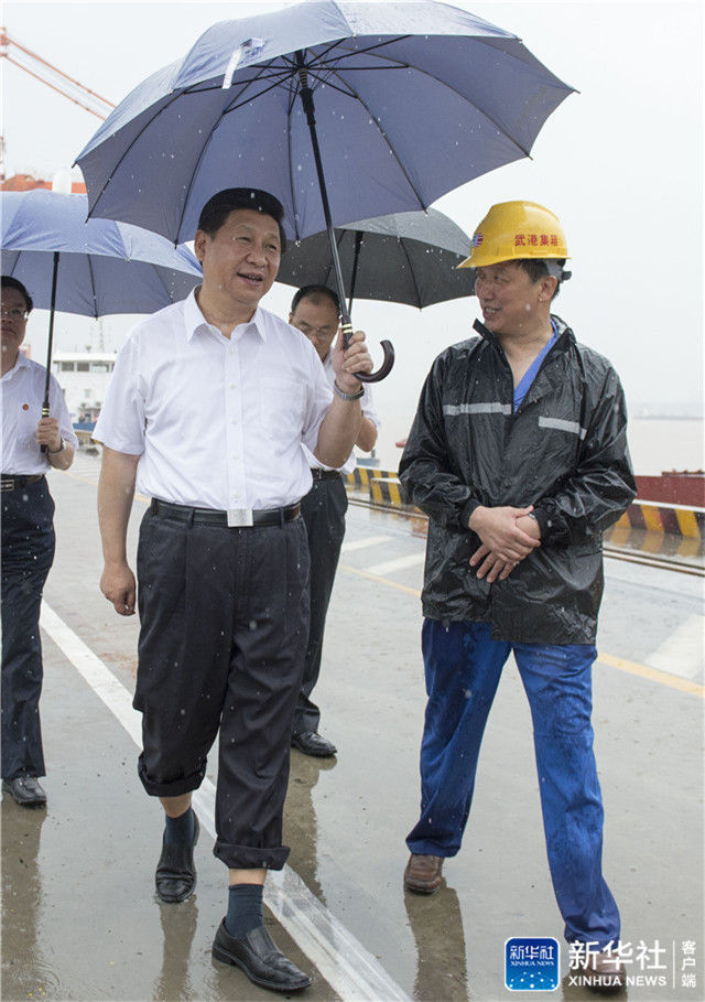 ↑2013年7月21日上午，習近平冒雨來到武漢新港陽邏集裝箱港區(qū)考察。記者 李學仁 攝